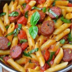 Kielbasa dorada con pasta y verduras coloridas en salsa cremosa